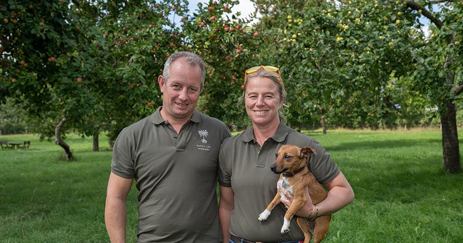 Barny and Emily Lee - Barny Lee Marquees owners stood in an apply orchard in Somerset